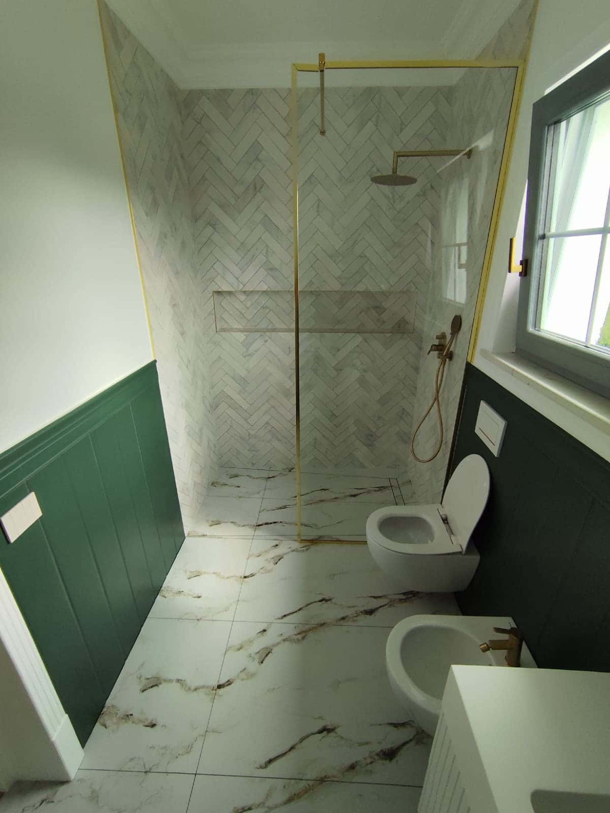 Duș walk-in cu mozaic în spic, profile aurii și lambriu verde