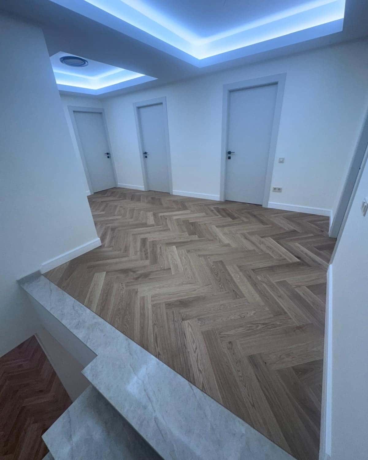 Hol cu parchet în spic și treaptă cu aspect de marmură