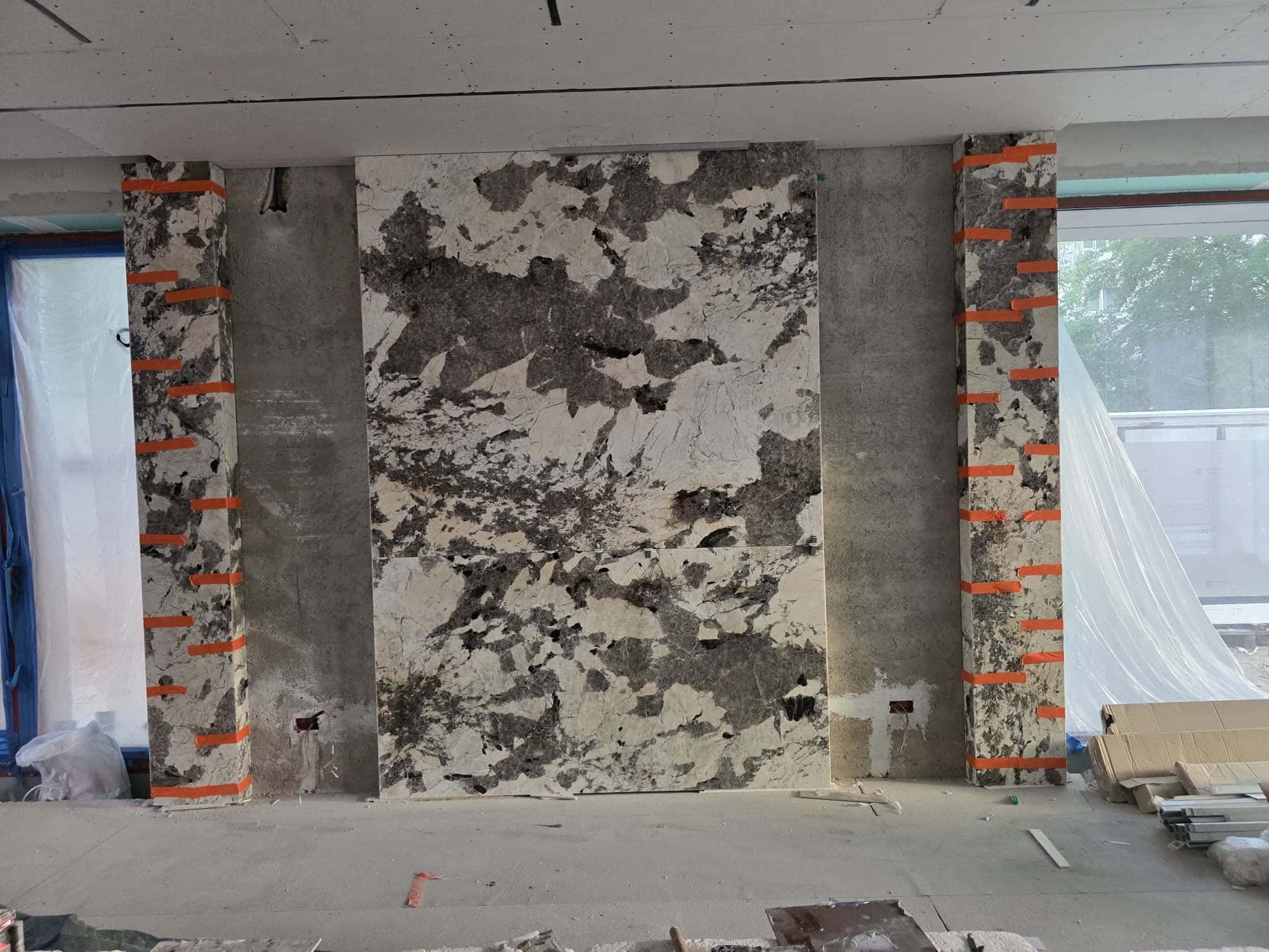 Perete cu plăci mari cu aspect de granit alb-negru, înainte să fie luminat din spate