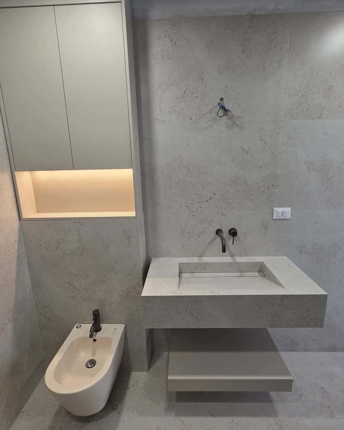 Lavoar placat din aceeași piatră gri-deschis ca pereții, cu nișă luminată