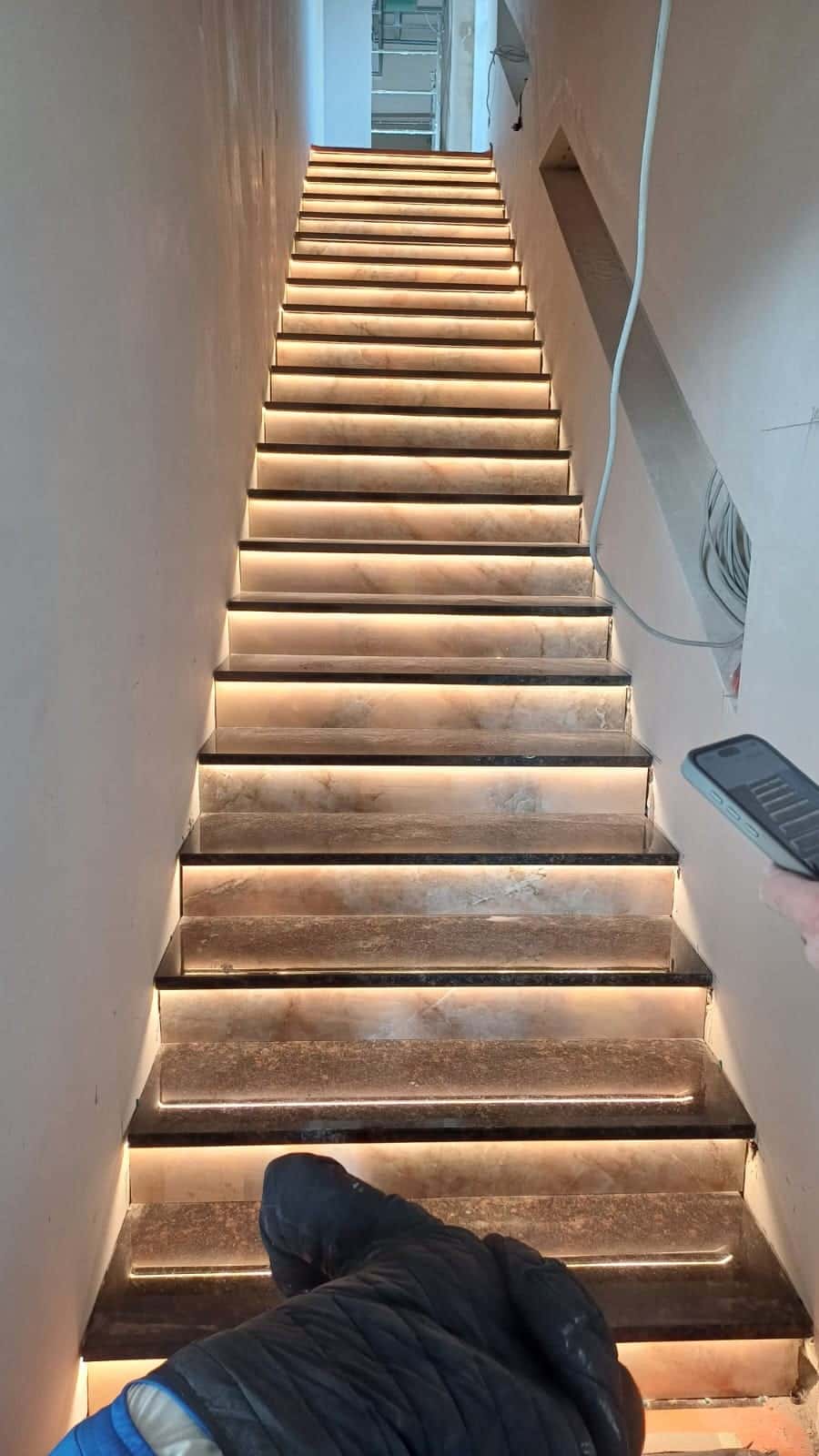 Scară cu trepte cu aspect de onix, luminate de dedesubt, în timpul lucrărilor