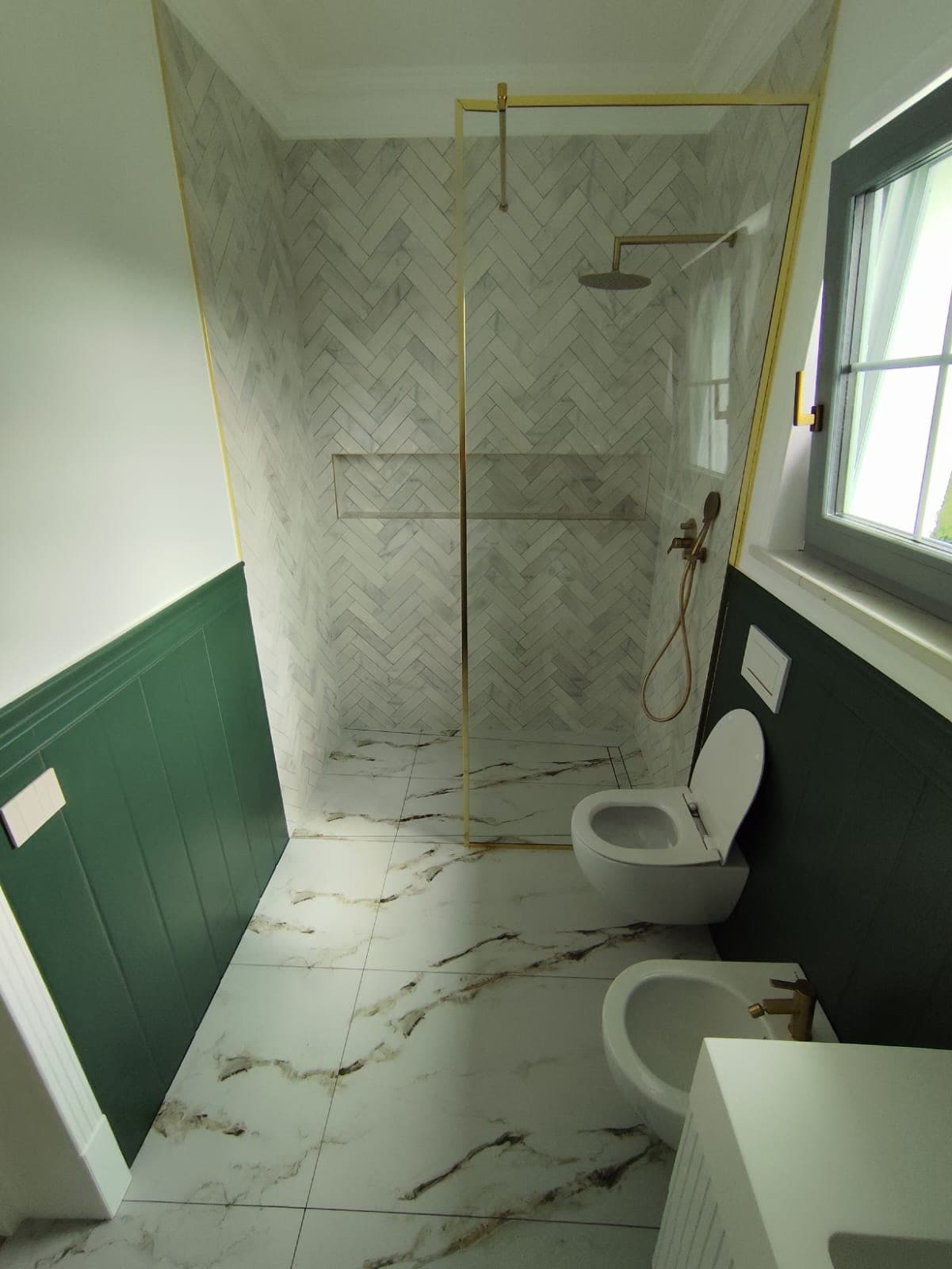 Duș walk-in cu mozaic în spic, profile aurii și lambriu verde