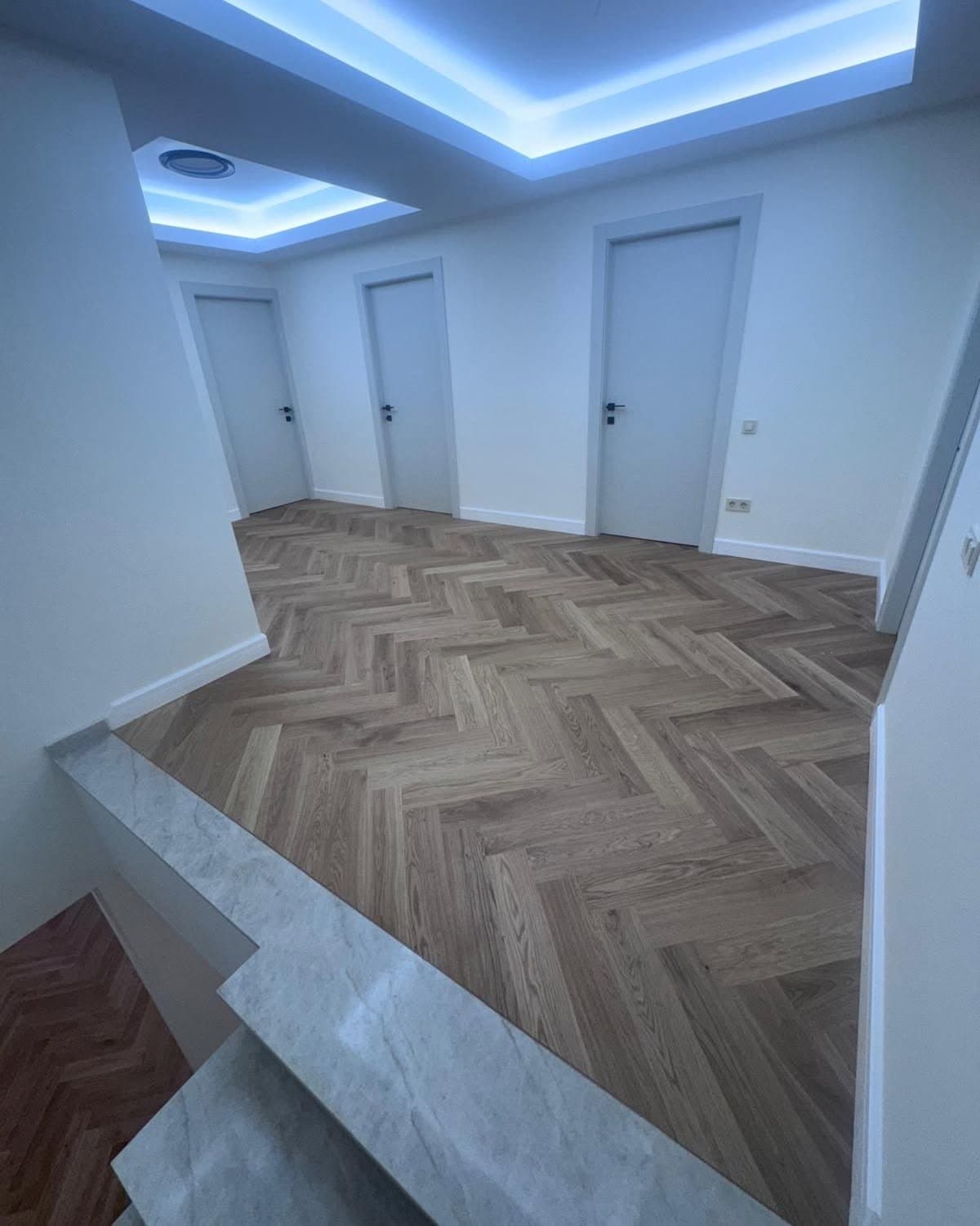 Hol cu parchet în spic și treaptă cu aspect de marmură